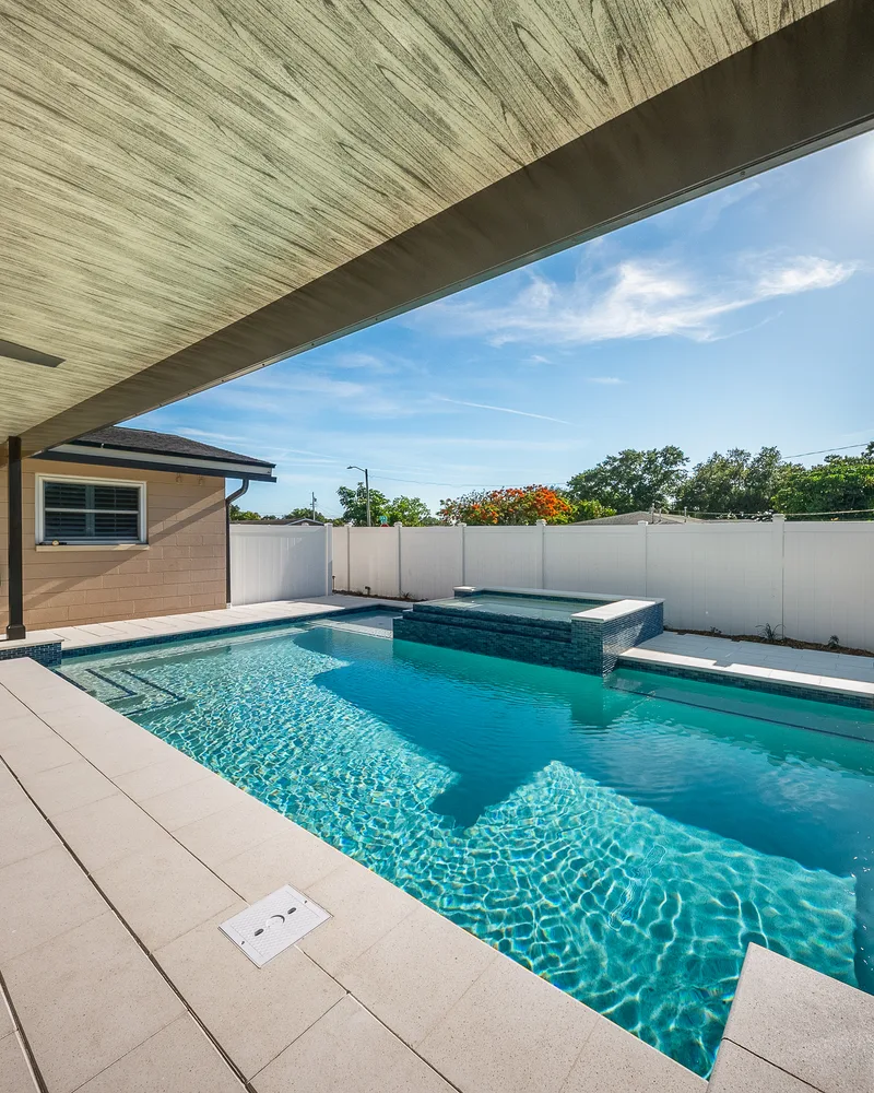 Custom pool with a water cascade and navy waterline tile built by Pool Perfection in Seminole