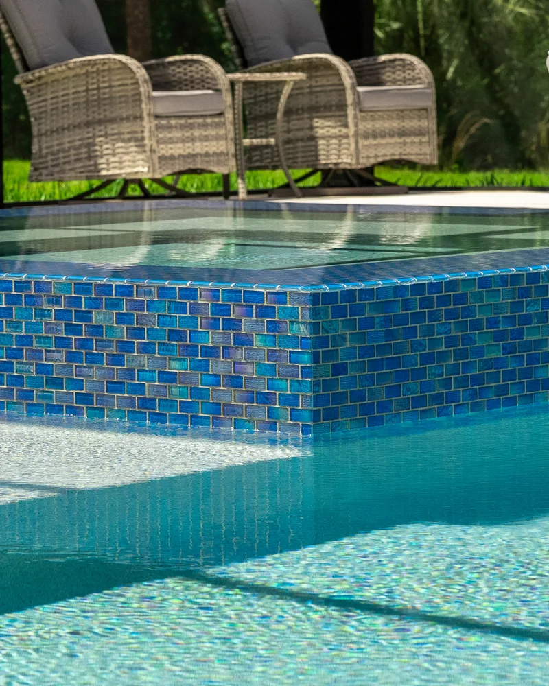 Custom pool and raised spa with Blue Lagoon glass tile built by Pool Perfection in Wesley Chapel